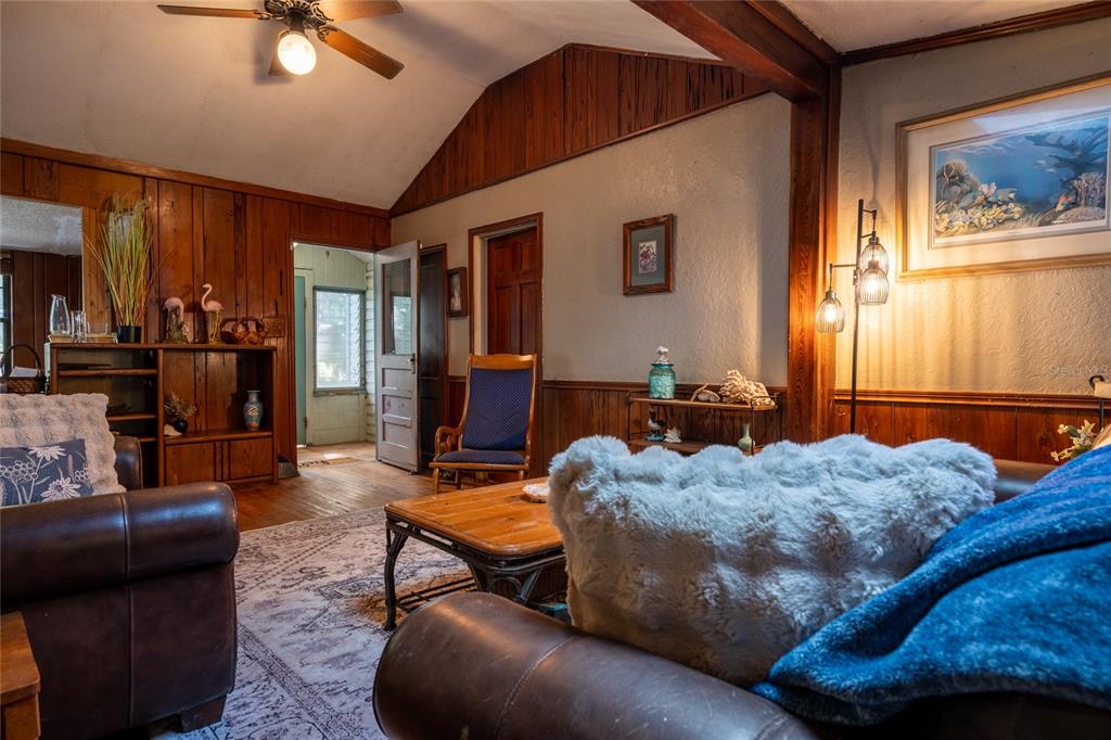 A living room features wood-paneled walls, a vaulted ceiling, and a leather sofa — 5560 PARK AVENUE, DE LEON SPRINGS, FL