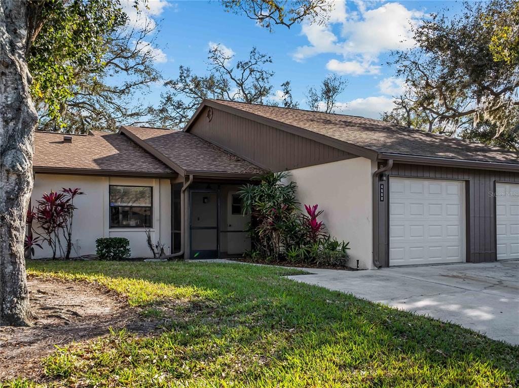 A single-story house with a beige stucco exterior, brown trim, and an attached garage — 4668 OAK HILL LANE UNIT 40, SARASOTA, FL