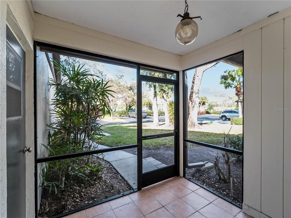 A screened-in porch with tiled flooring, a ceiling light fixture, and views of the outdoors — 4668 OAK HILL LANE UNIT 40, SARASOTA, FL