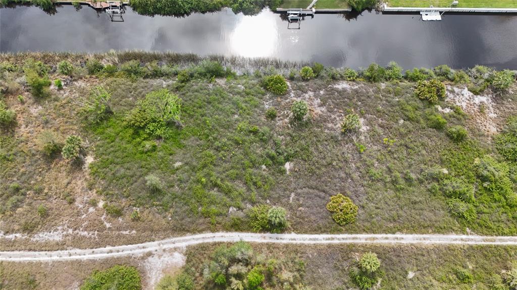 An aerial view of a vacant, brush-covered lot bordering a narrow canal — 27399 SOLOMON DRIVE, PUNTA GORDA, FL