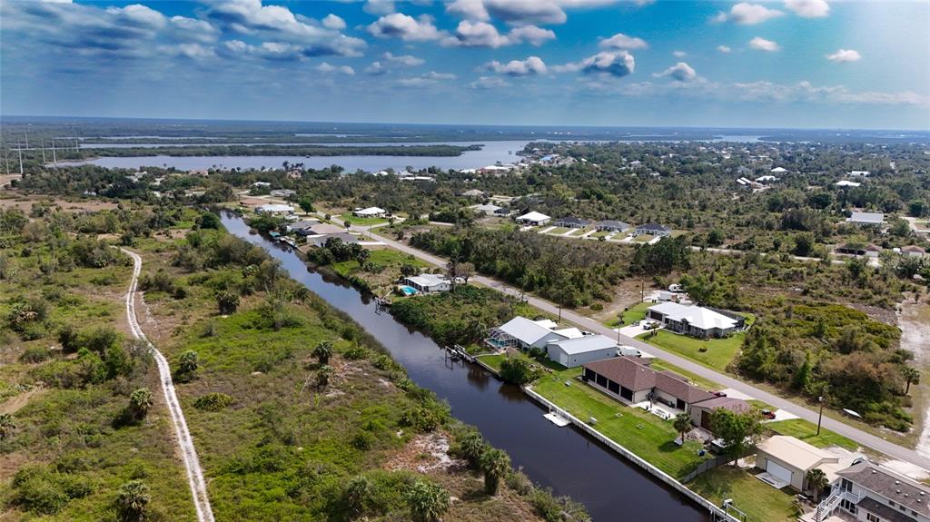 An aerial view shows a canal running through a residential area with scattered houses — 27399 SOLOMON DRIVE, PUNTA GORDA, FL