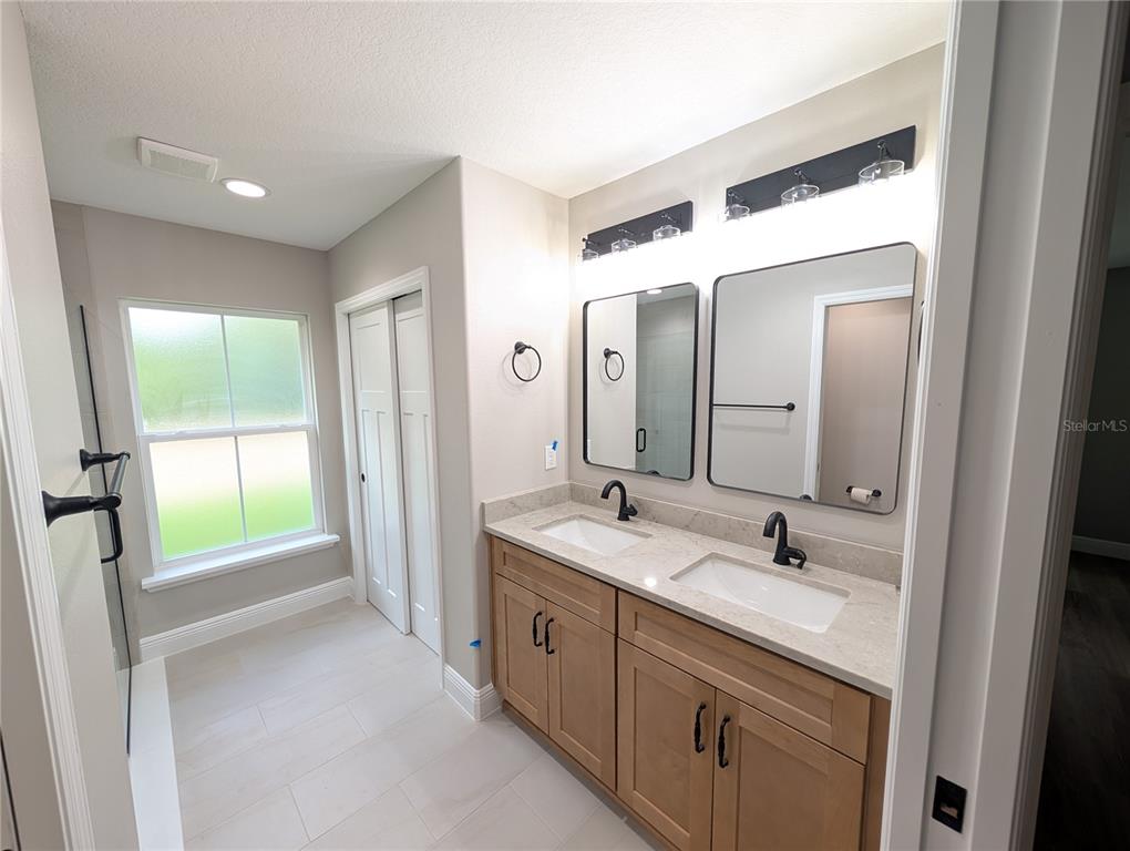 A bathroom features a double vanity with light wood cabinets, quartz countertops, and dual mirrors — 12397 SW 76TH LANE, DUNNELLON, FL