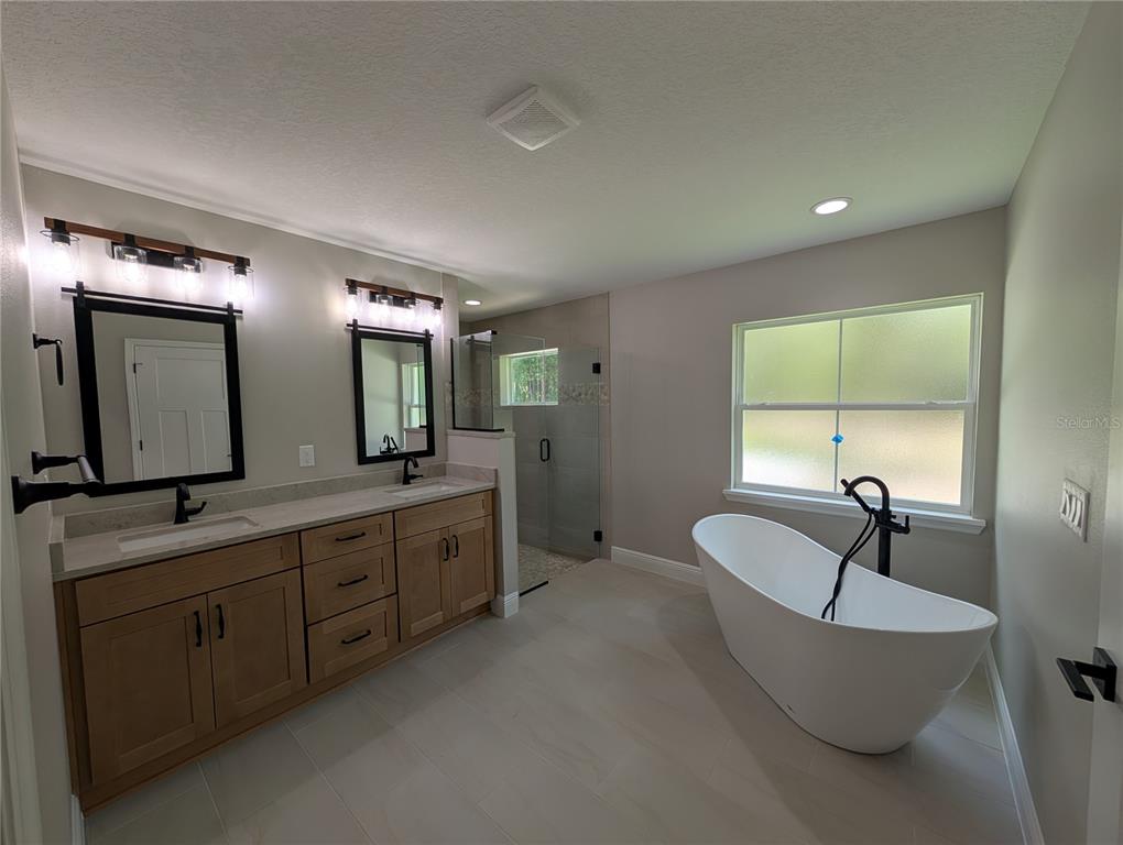 A modern bathroom features a double vanity with wood cabinets, a freestanding tub, and a shower — 12397 SW 76TH LANE, DUNNELLON, FL