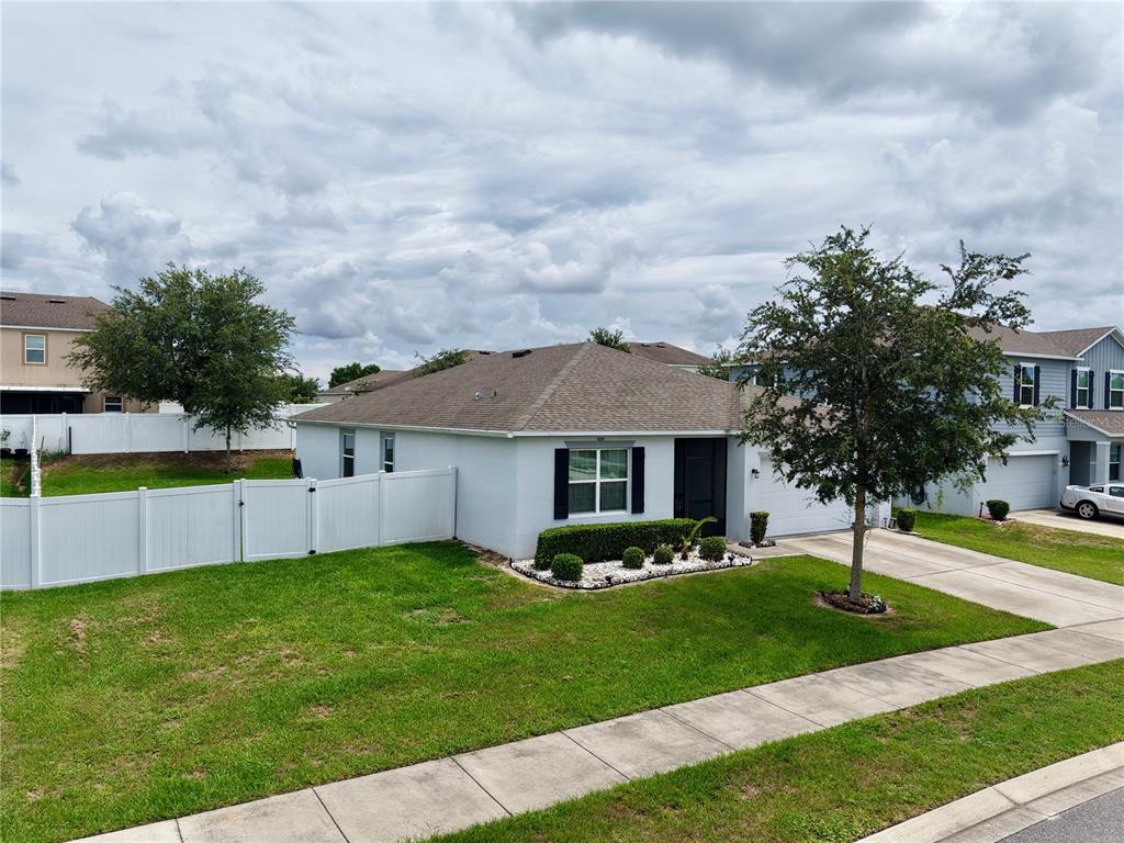 A single-story house with a white exterior, a gray roof, and a white vinyl fence — 15280 WHITE TAIL LOOP, MASCOTTE, FL