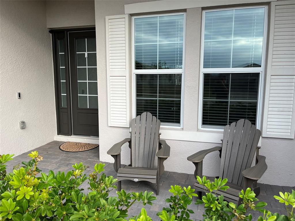 Two gray Adirondack chairs sit on a paved patio in front of a house entrance — 14580 PONCE DE LEON TRAIL, PORT CHARLOTTE, FL