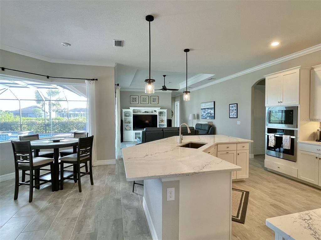 A kitchen with a white island and countertops opens into a living area with tile floors — 14580 PONCE DE LEON TRAIL, PORT CHARLOTTE, FL