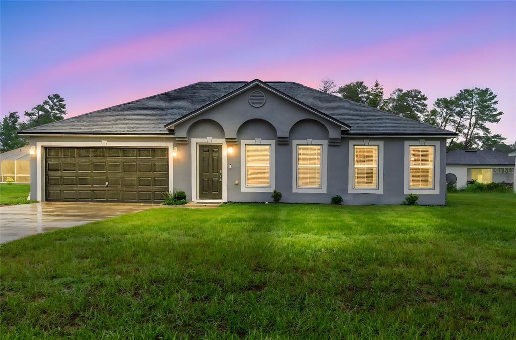 A single-story gray house with a two-car garage and a front lawn at dusk — 3750 SW 127TH LANE ROAD, OCALA, FL