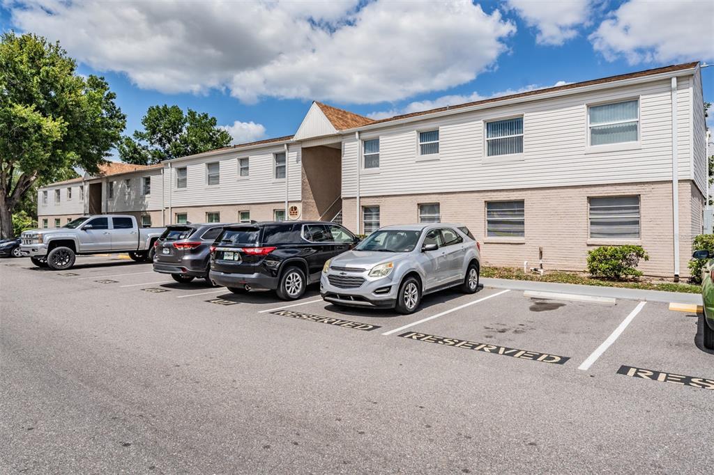 A two-story apartment building with a parking lot featuring reserved spaces in the foreground — 7210 N MANHATTAN AVENUE UNIT 1913, TAMPA, FL