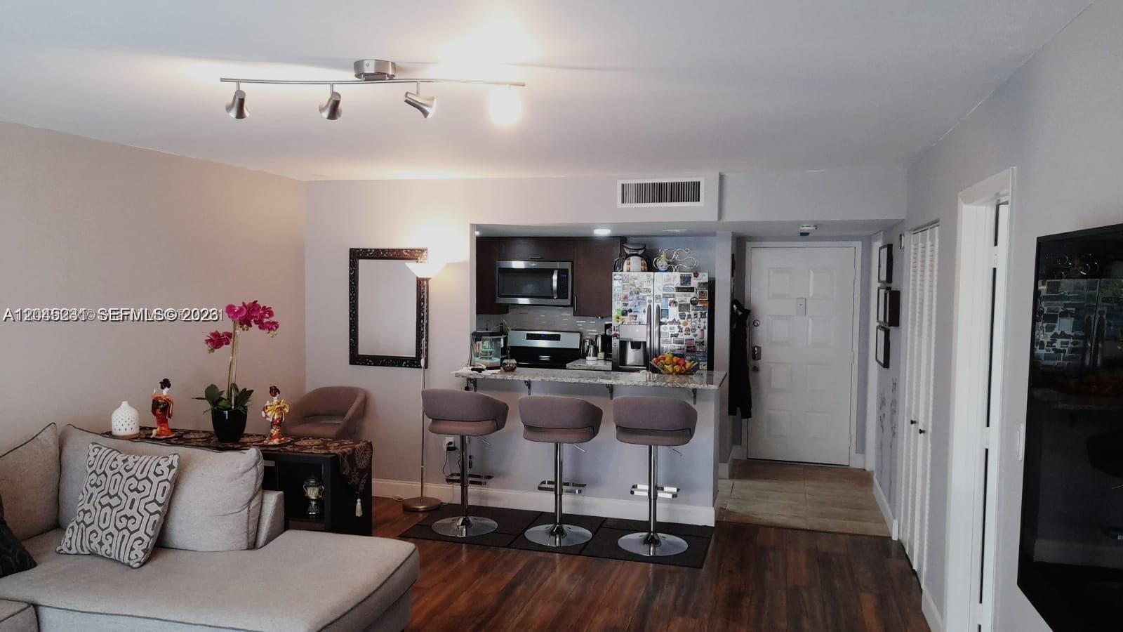 A living room with a sofa, a breakfast bar with three stools, and an open kitchen — 5530 NW 44th St # 408C, Lauderhill FL 33319, LAUDERHILL, FL
