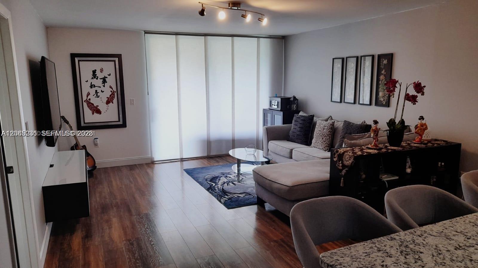 A living room features a grey sectional sofa, wood flooring, and Asian-inspired wall art — 5530 NW 44th St # 408C, Lauderhill FL 33319, LAUDERHILL, FL