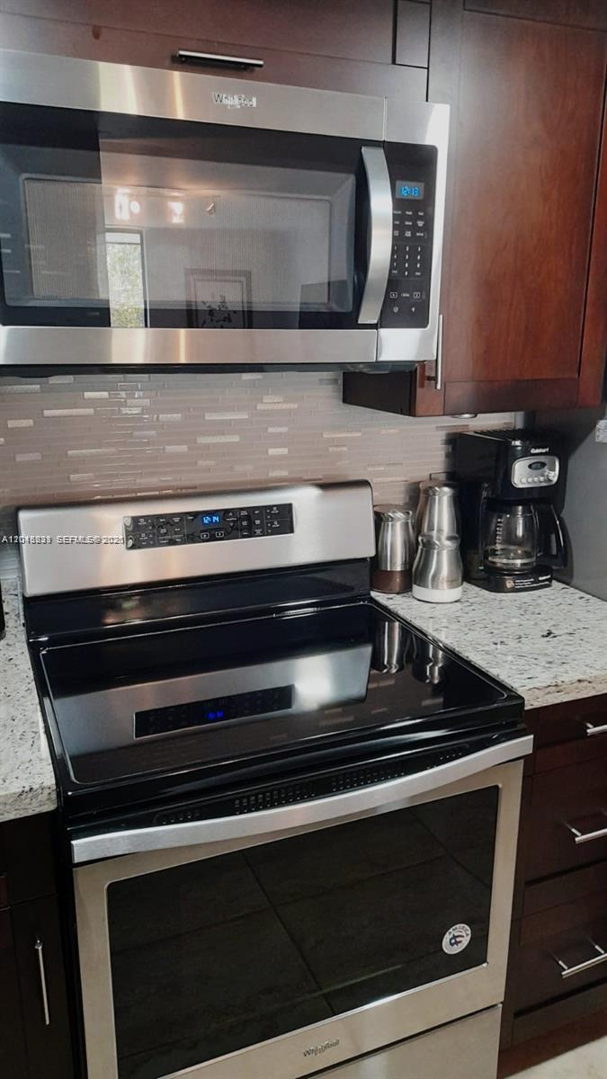 A kitchen features dark wood cabinets, stainless steel appliances, and a granite countertop — 5530 NW 44th St # 408C, Lauderhill FL 33319, LAUDERHILL, FL