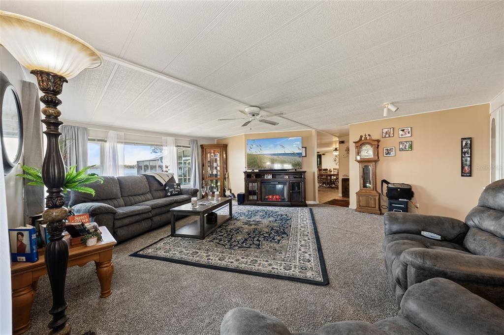 A living room features gray carpet, a dark sofa, a fireplace console, and a grandfather clock — 121 BONNIE DRIVE, AUBURNDALE, FL