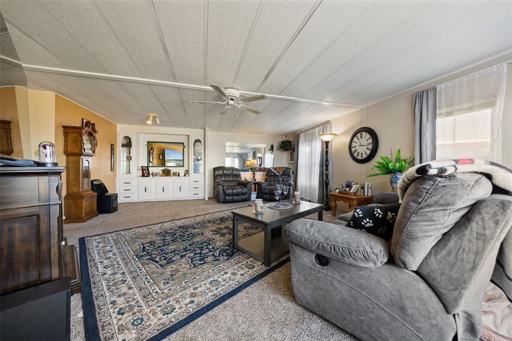 A living room features a large area rug, two recliners, and a built-in media console — 121 BONNIE DRIVE, AUBURNDALE, FL