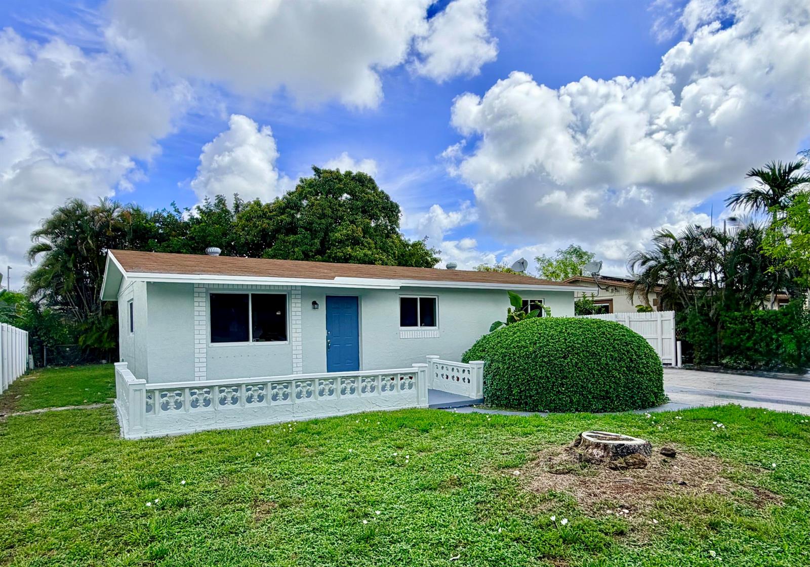 A light blue single-story house features a brown roof, a blue door, and a decorative fence — 2811 NW 8th Street, Pompano Beach FL 33069, POMPANO BEACH, FL