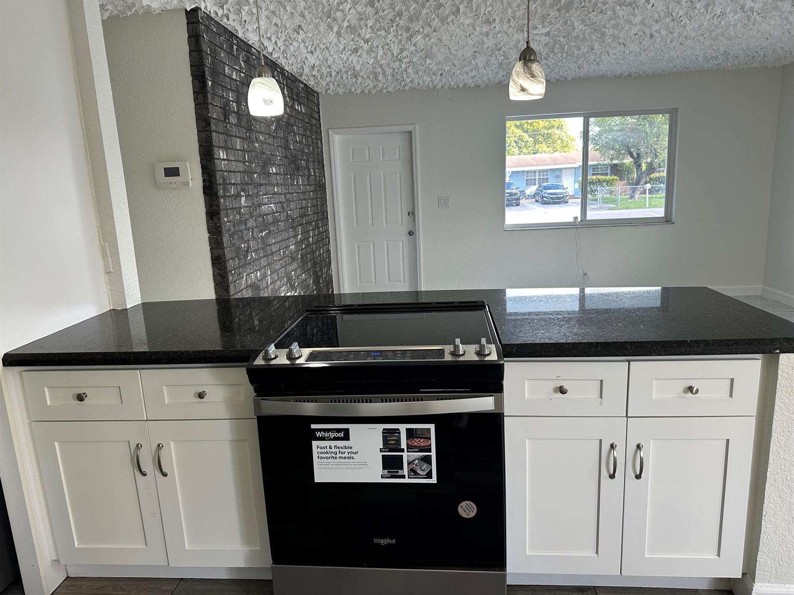 A kitchen island features a black electric range, white cabinets, and a dark granite countertop — 2811 NW 8th Street, Pompano Beach FL 33069, POMPANO BEACH, FL