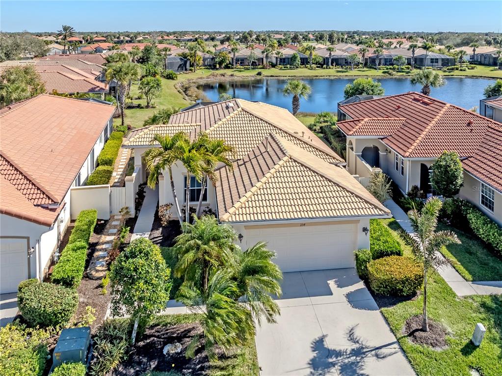 An aerial view shows a tan house with a tiled roof, driveway, and palm trees — 254 MESTRE PLACE, NORTH VENICE, FL