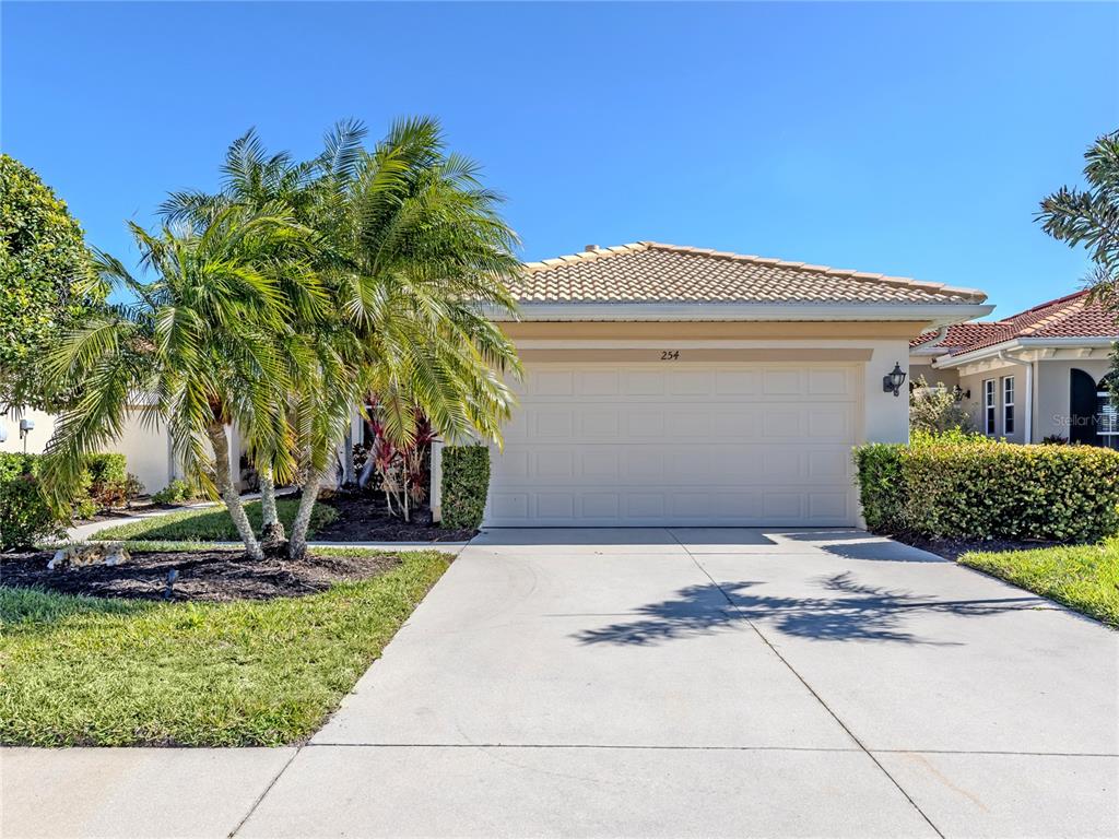 A single-story house exterior features a two-car garage, a palm tree, and a concrete driveway — 254 MESTRE PLACE, NORTH VENICE, FL
