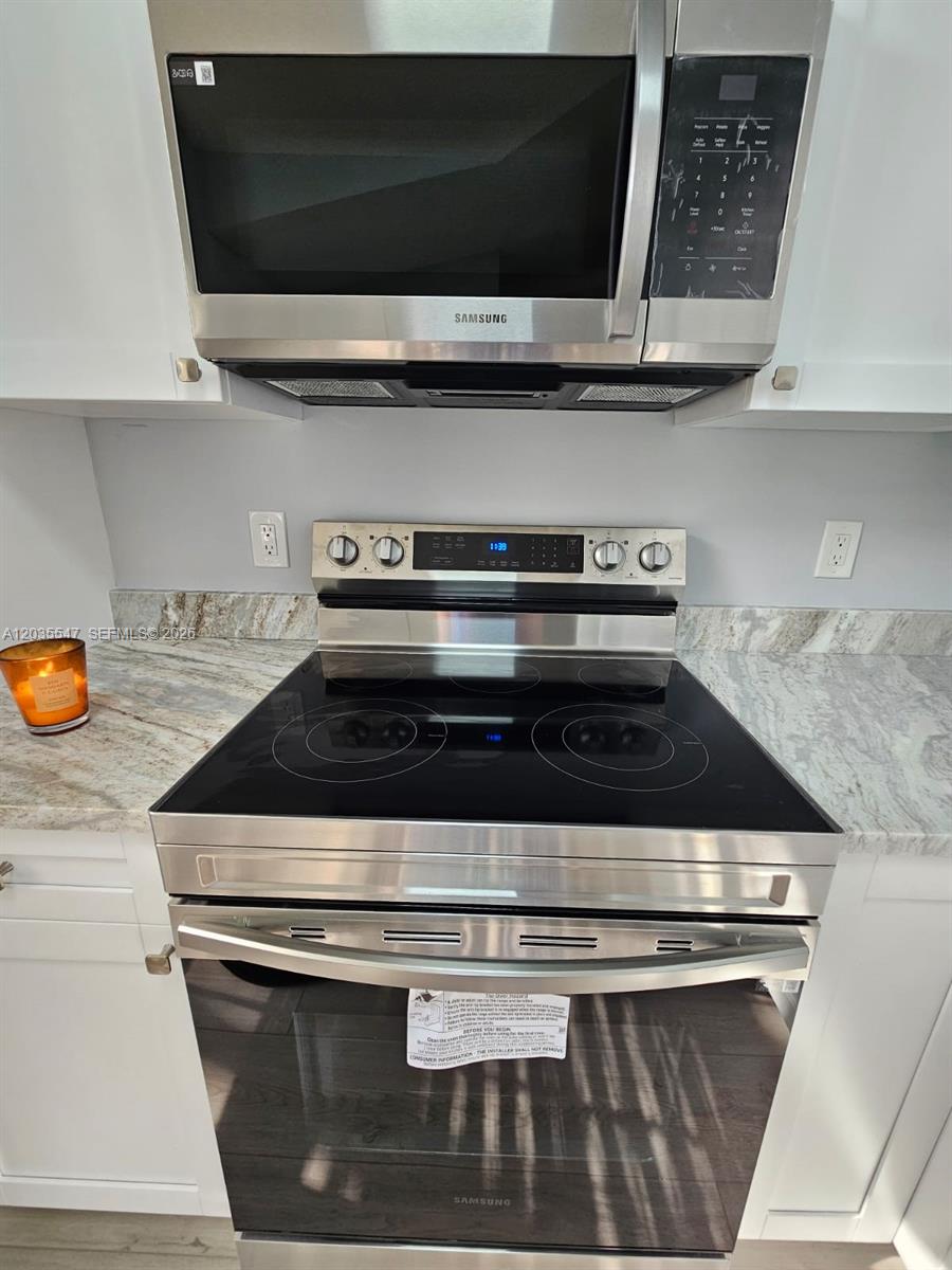 A stainless steel Samsung microwave and electric range are installed between white kitchen cabinets — 10823 NW 3rd Ct, Pembroke Pines FL 33026, PEMBROKE PINES, FL