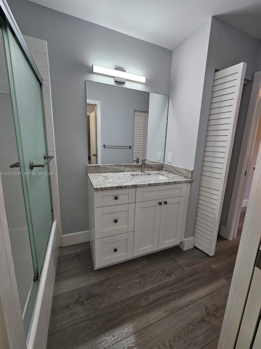 A bathroom features a white vanity with a granite countertop, a mirror, and a shower — 10823 NW 3rd Ct, Pembroke Pines FL 33026, PEMBROKE PINES, FL