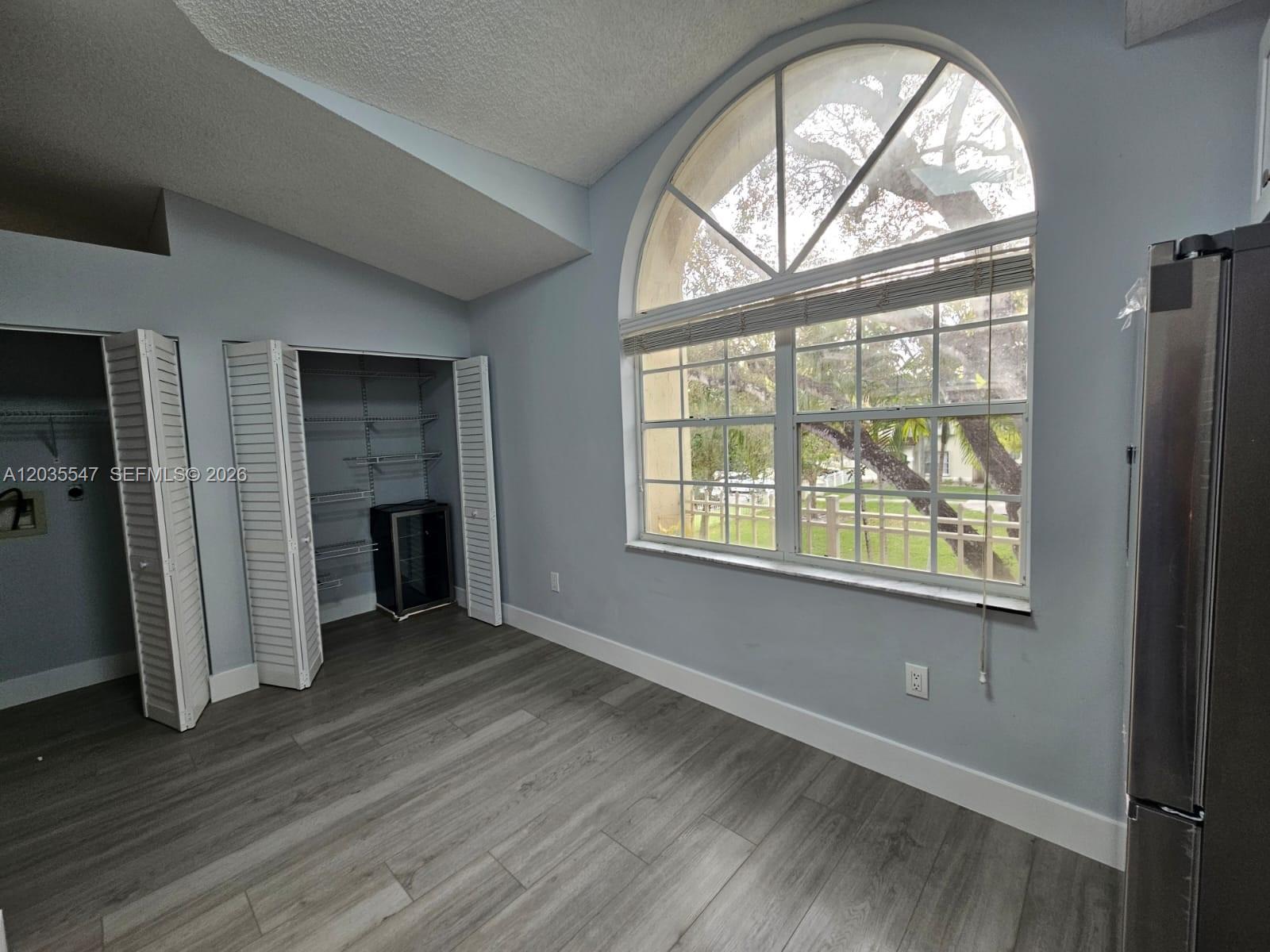 A room with light gray walls, wood-look flooring, a large arched window, and two closets — 10823 NW 3rd Ct, Pembroke Pines FL 33026, PEMBROKE PINES, FL