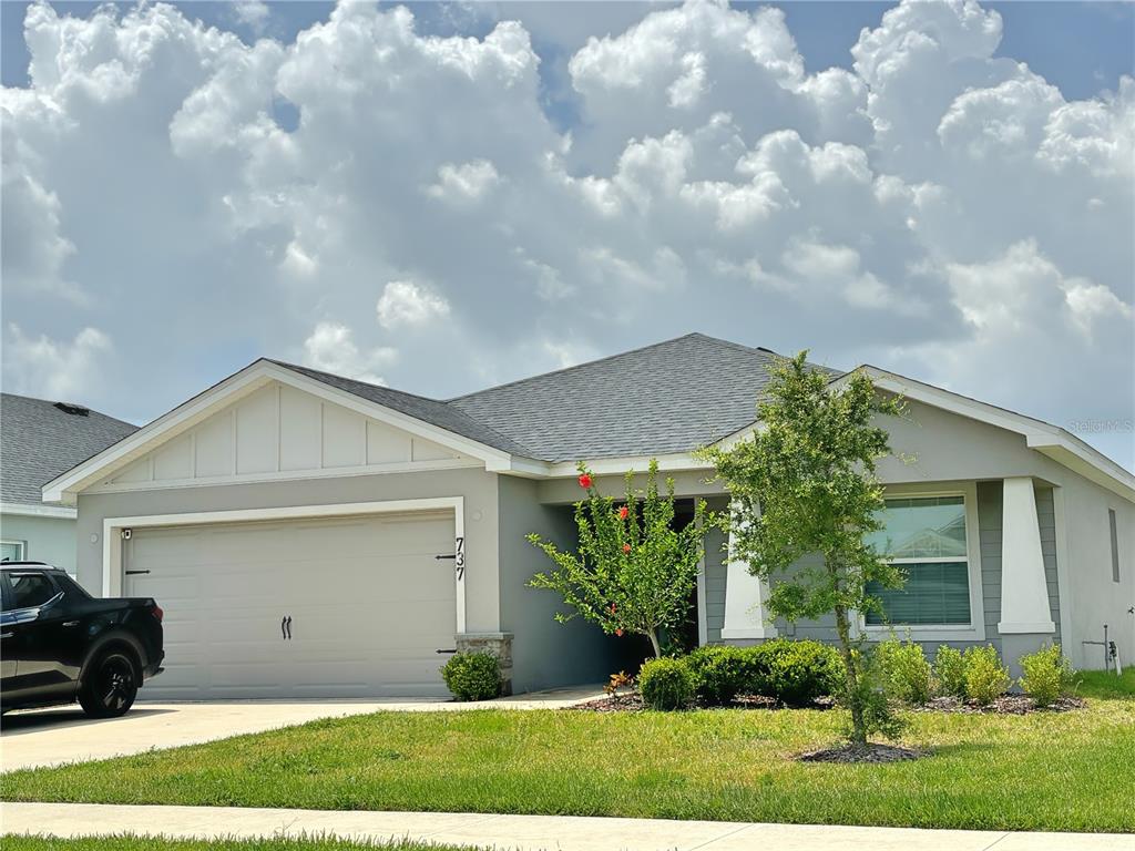A single-story suburban house with a gray exterior, a two-car garage, and a front lawn — 737 DAPHNE DRIVE, POLK CITY, FL