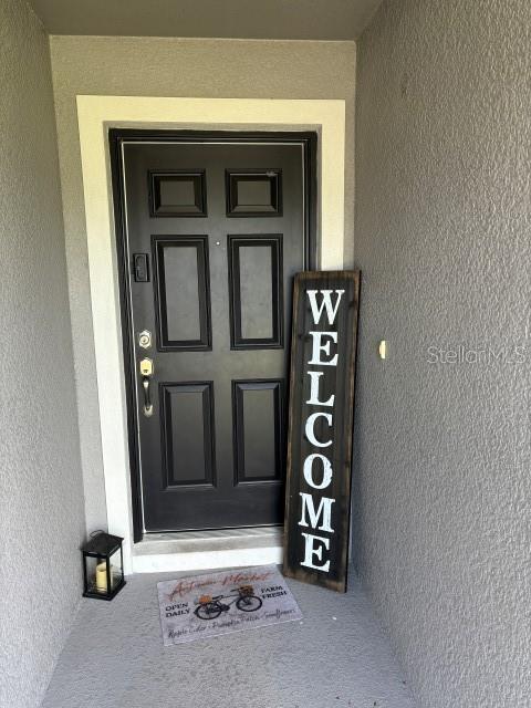 A black front door features a vertical welcome sign and a decorative mat on the porch — 737 DAPHNE DRIVE, POLK CITY, FL