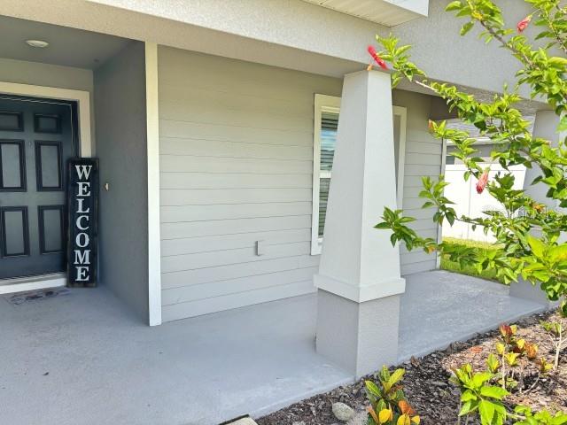 A covered front porch features a dark door with a welcome sign and a column — 737 DAPHNE DRIVE, POLK CITY, FL