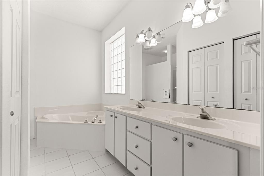 A bathroom features a double vanity, a soaking tub, and a large wall mirror — 2380 NW 53RD AVENUE ROAD, OCALA, FL