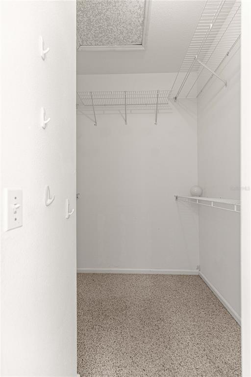 A walk-in closet with white walls, wire shelving, wall hooks, and speckled flooring — 2380 NW 53RD AVENUE ROAD, OCALA, FL