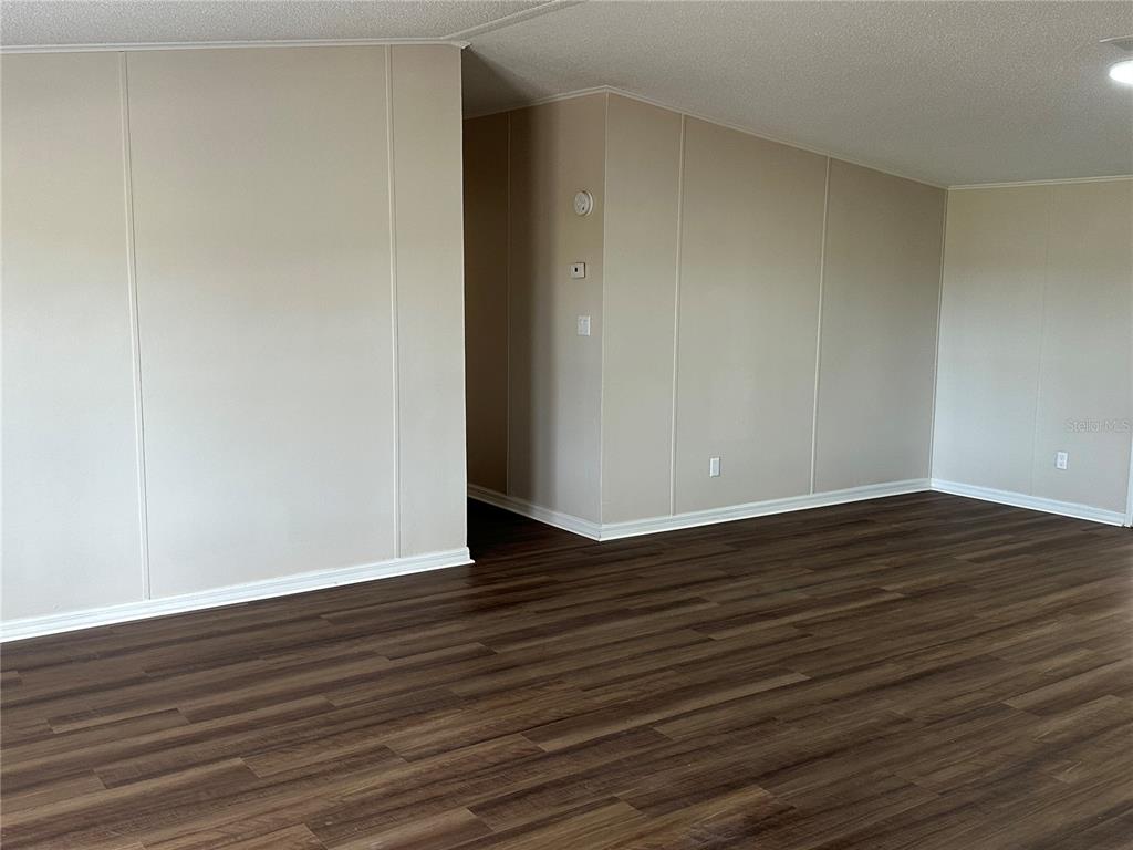 An interior view of a room with beige paneled walls and dark wood-look flooring — 4128 W BELLA VISTA STREET, LAKELAND, FL