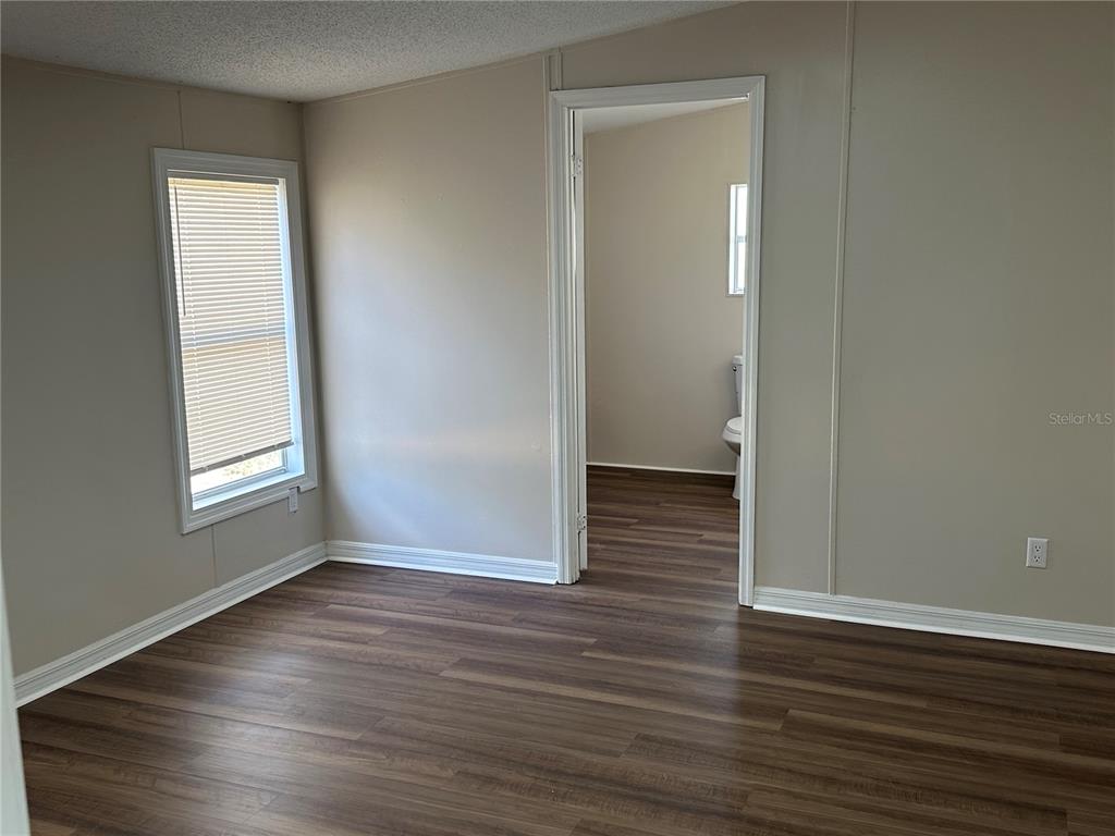 A room with wood-look flooring and a doorway leading to a bathroom — 4128 W BELLA VISTA STREET, LAKELAND, FL
