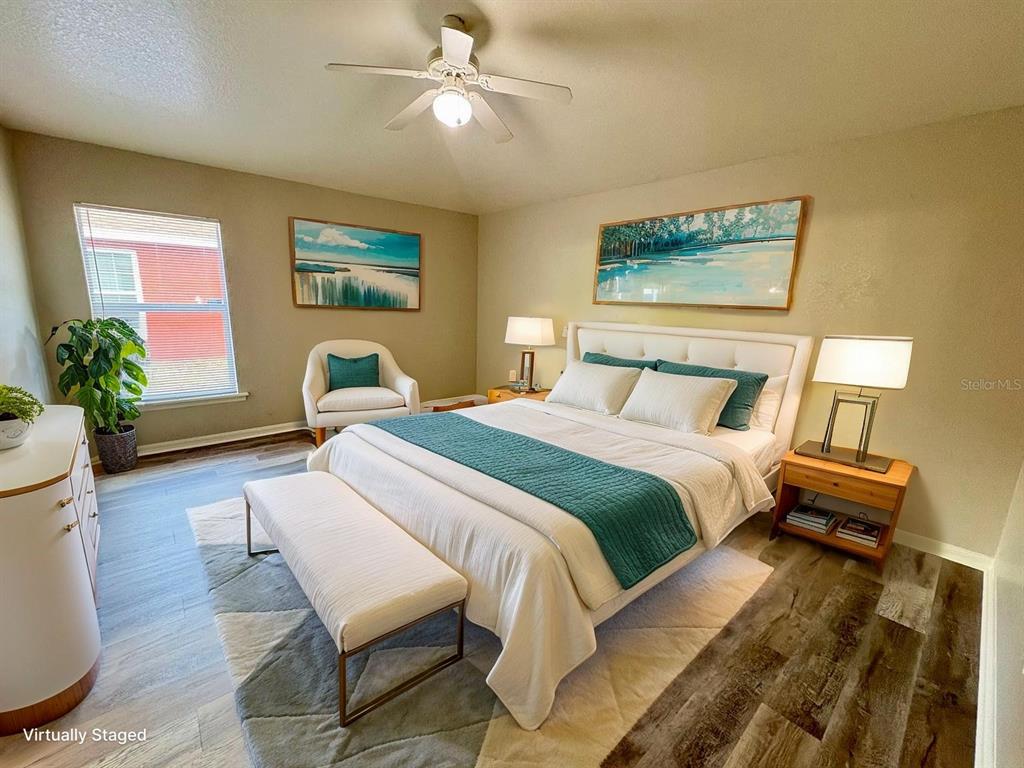 A bedroom features a bed with teal accents, a ceiling fan, and wood-look flooring — 609 TAMARIN LANE, POINCIANA, FL