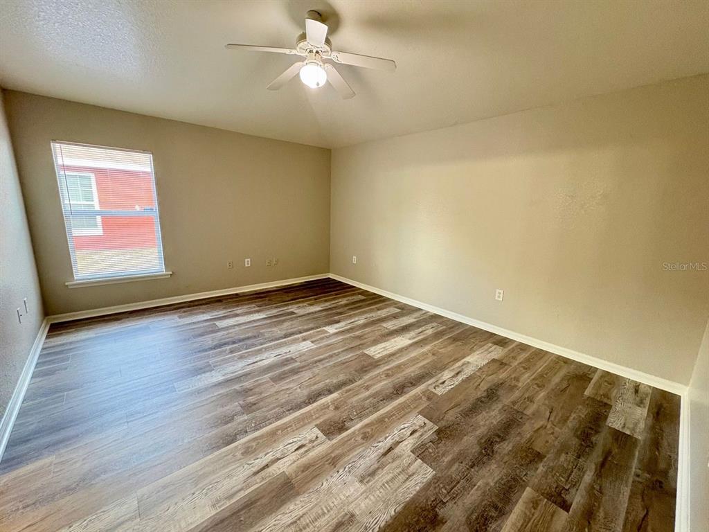 An empty bedroom features light-colored walls, a ceiling fan, and wood-look flooring — 609 TAMARIN LANE, POINCIANA, FL