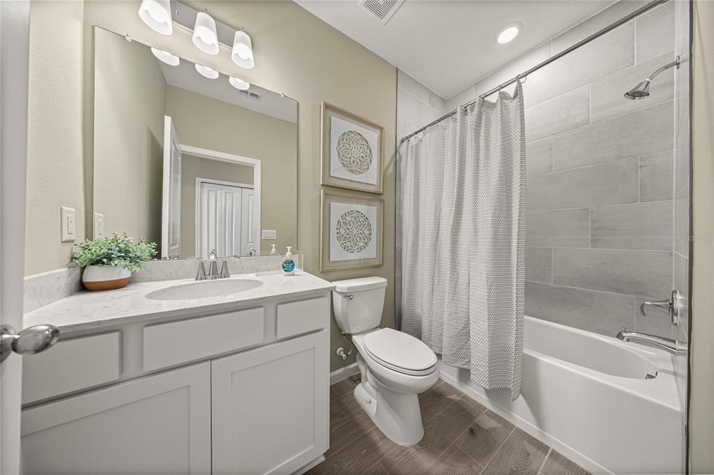 A bathroom features a white vanity, a toilet, and a shower-tub combination with gray tiles — 19376 SW 77TH LOOP, DUNNELLON, FL