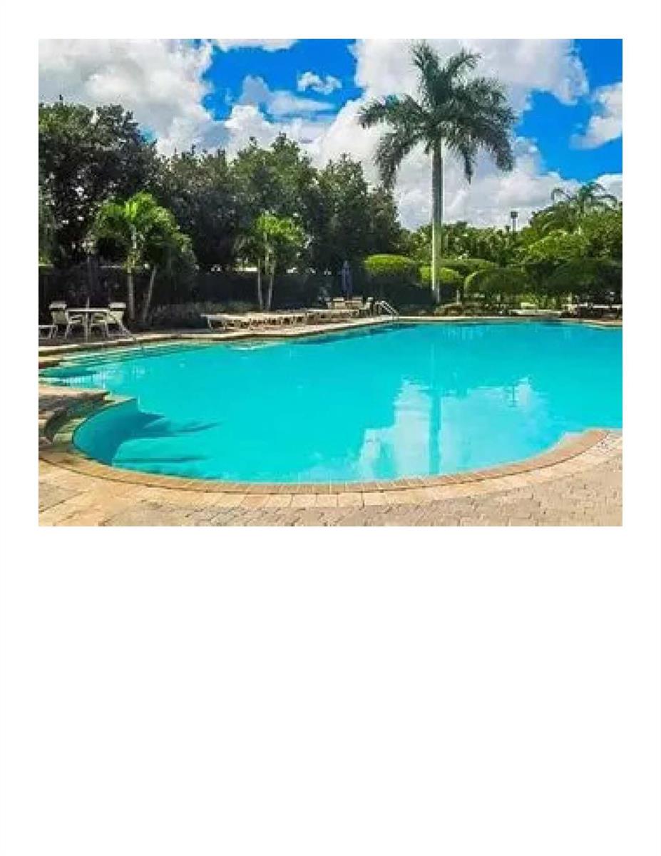 A swimming pool with a brick paver deck is surrounded by palm trees and landscaping — 112 Lancaster Way, Royal Palm Beach FL 33414, ROYAL PALM BEACH, FL