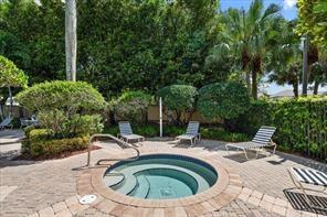 A circular hot tub sits on a paved patio surrounded by lush landscaping and lounge chairs — 112 Lancaster Way, Royal Palm Beach FL 33414, ROYAL PALM BEACH, FL
