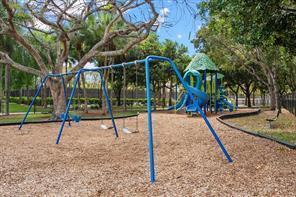 A playground features a blue swing set and a climbing structure on a wood-chipped surface — 112 Lancaster Way, Royal Palm Beach FL 33414, ROYAL PALM BEACH, FL