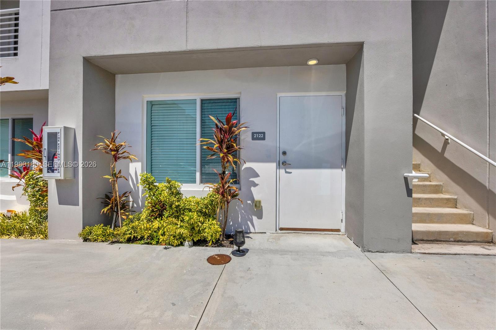 The exterior view shows a white door, a window, landscaping, and concrete stairs — 2555 NE 193rd St # 2122, Miami FL 33180, MIAMI, FL