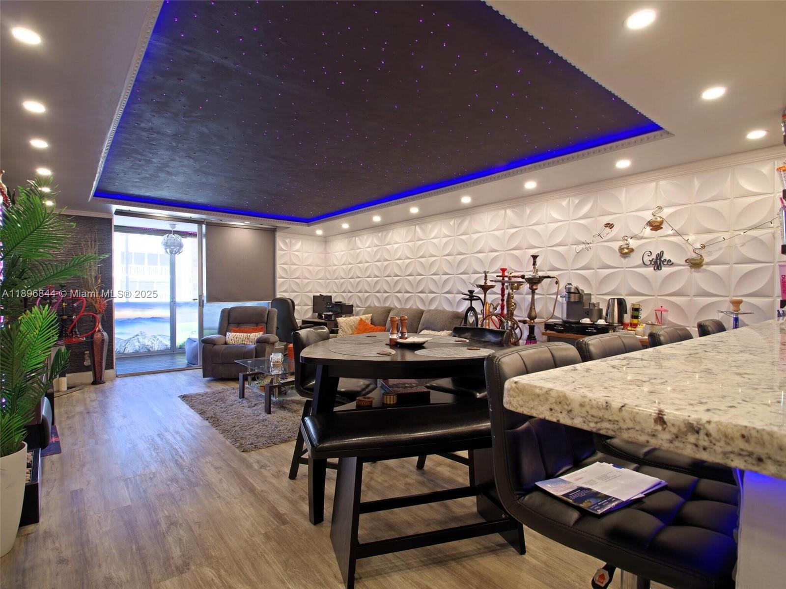 A living and dining area features a starlit ceiling, textured wall panels, and a balcony — 420 NE 12th Ave # 401, Hallandale Beach FL 33009, HALLANDALE BEACH, FL