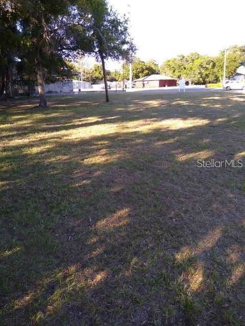 A grassy, vacant lot features several trees and a distant building under a clear sky — 1512 S MISSOURI AVENUE, CLEARWATER, FL