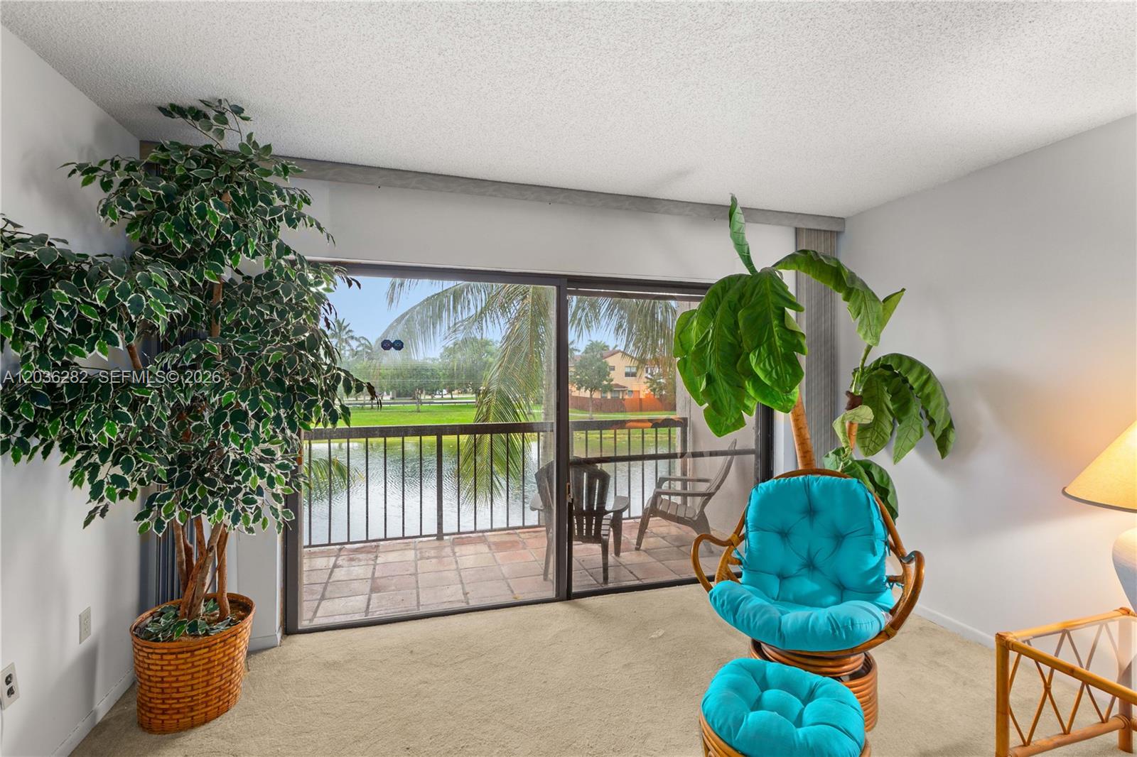 A living room features a sliding glass door opening to a balcony overlooking a lake — 10155 NW 9th St Cir # 202, Miami FL 33172, MIAMI, FL