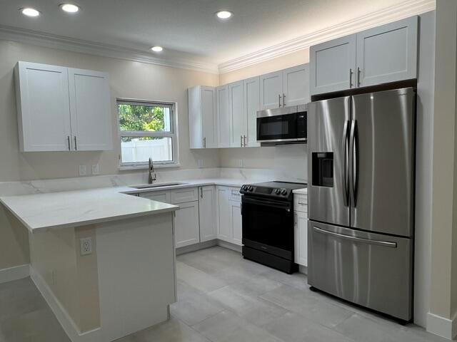 A kitchen features white cabinets, stainless steel appliances, and light-colored countertops — 239 Leland Lane, FL 33463, FL
