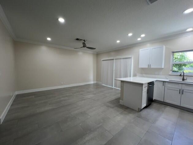 An open-concept kitchen and living area features gray tile flooring and white cabinetry — 239 Leland Lane, FL 33463, FL