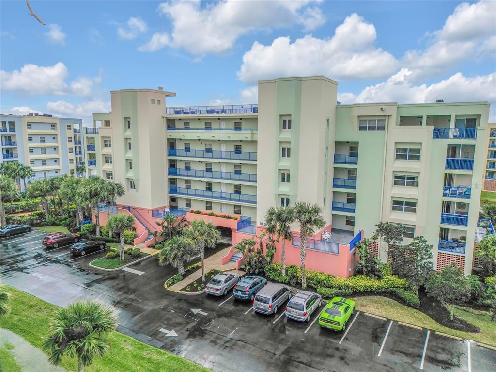 An exterior view of a multi-story apartment building with a parking lot in the foreground — 5300 S ATLANTIC AVENUE UNIT 16-502, NEW SMYRNA BEACH, FL