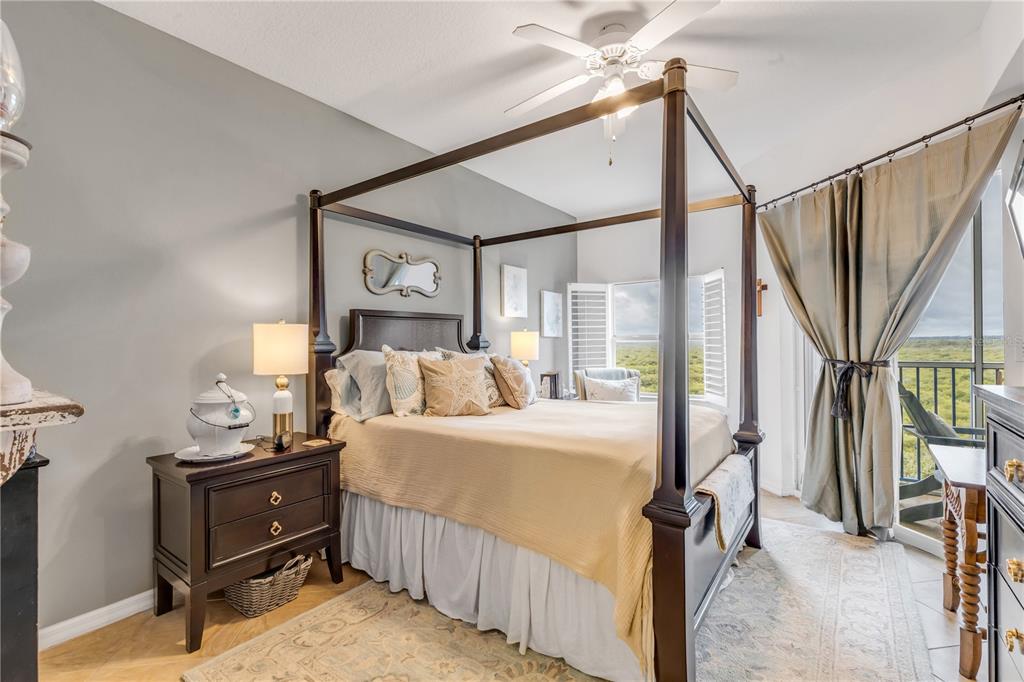 A bedroom features a dark wood four-poster bed, a nightstand, and a balcony view — 5300 S ATLANTIC AVENUE UNIT 16-502, NEW SMYRNA BEACH, FL