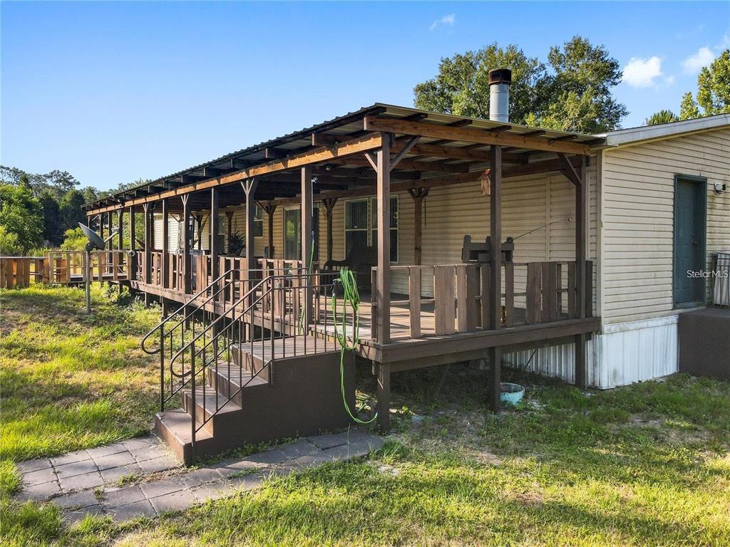 A mobile home features a large wooden deck with a covered porch and metal roof — 13921 PINE MEADOW ROAD, KATHLEEN, FL