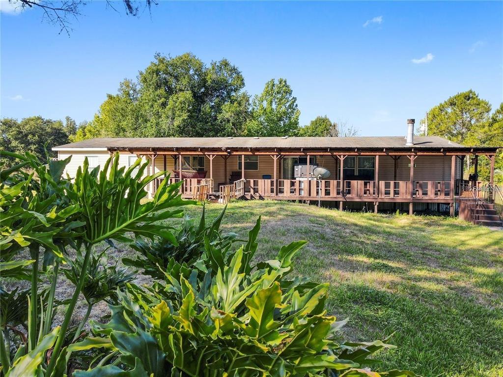 A single-story house with a long wooden porch and a metal roof sits on grass — 13921 PINE MEADOW ROAD, KATHLEEN, FL