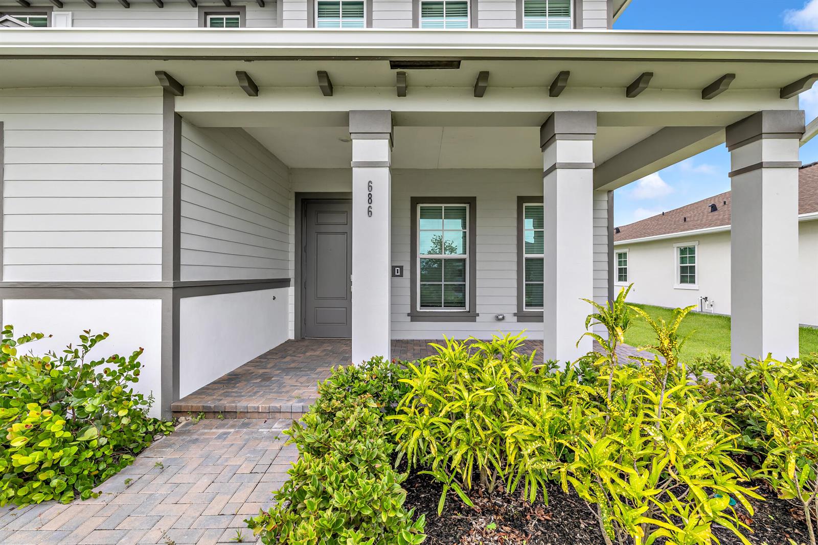 The front exterior of a house features a covered porch, gray siding, and landscaping — 686 Hookline Circle, Loxahatchee FL 33470, LOXAHATCHEE, FL