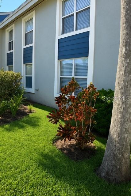 The exterior of a house features light gray siding, blue accents, and a small garden — 4860 S ATLANTIC AVENUE UNIT 1010, NEW SMYRNA BEACH, FL