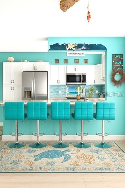 A kitchen features turquoise walls, white cabinetry, five matching bar stools, and a sea-themed rug — 4860 S ATLANTIC AVENUE UNIT 1010, NEW SMYRNA BEACH, FL